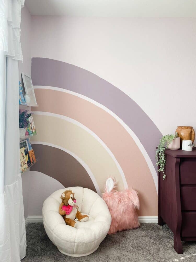 corner of princess themed bedroom with a rainbow mural and reading corner