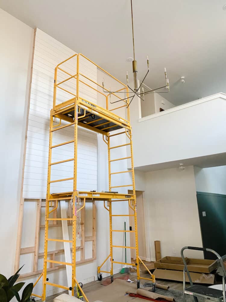 living room with scaffolding and a two-story fireplace being built