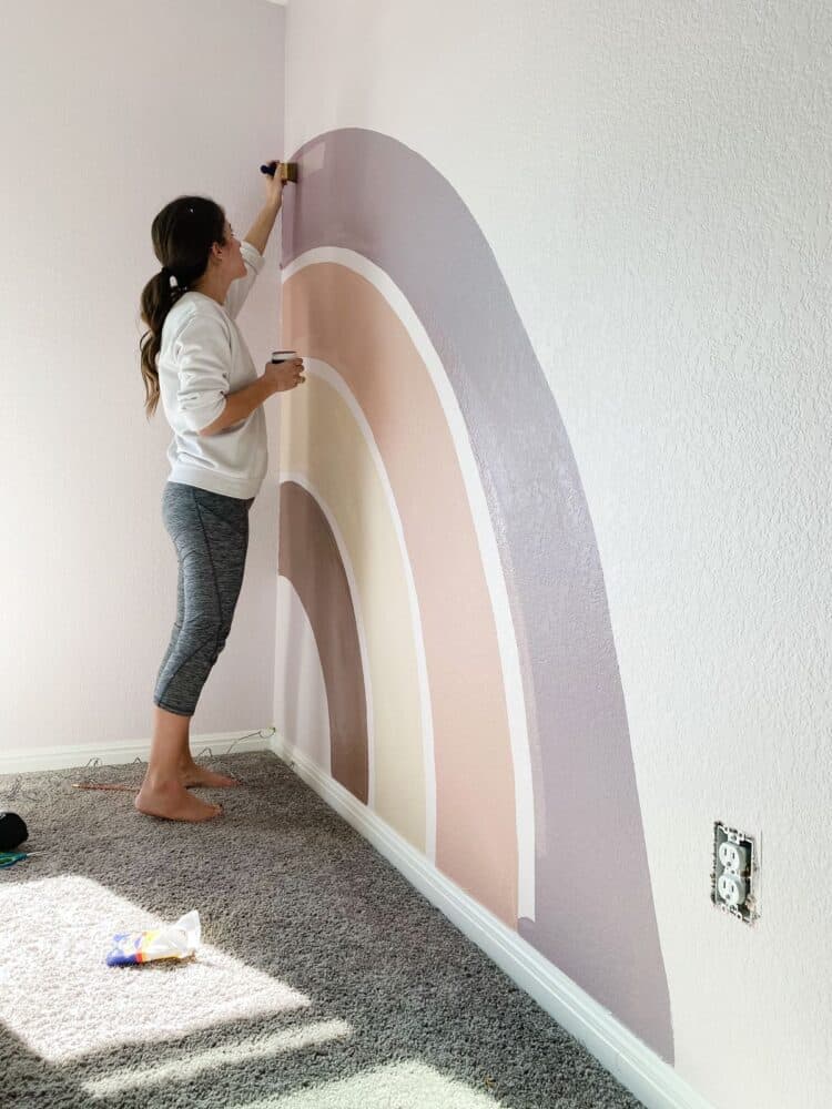 woman painting a rainbow mural