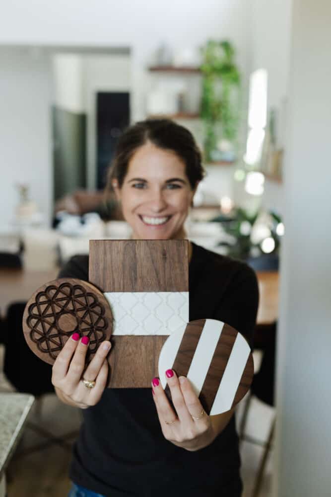 woman holding three wood and corian hot plates