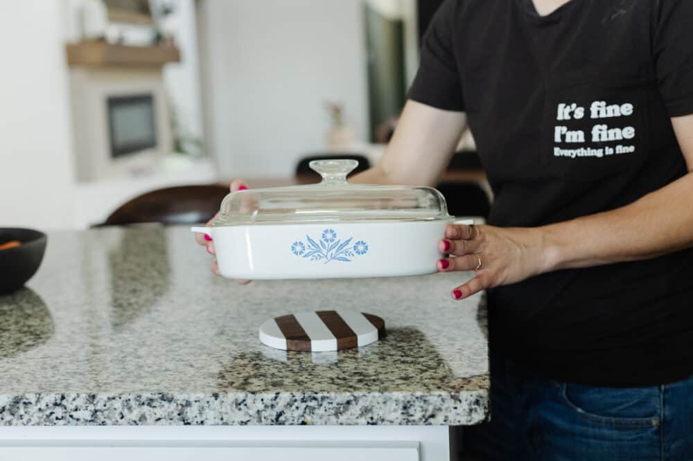 Woman setting a hot dish on a walnut and corian trivet