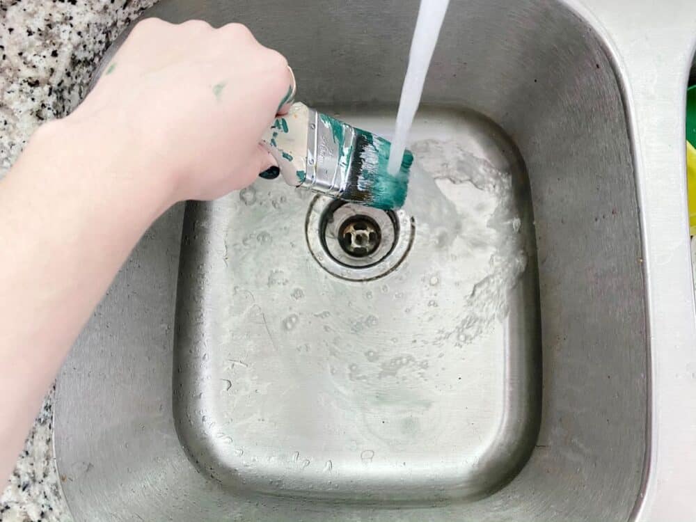 woman's hand rinsing a paintbrush