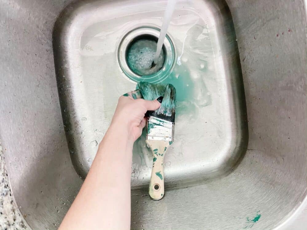 woman cleaning a paintbrush with dish soap