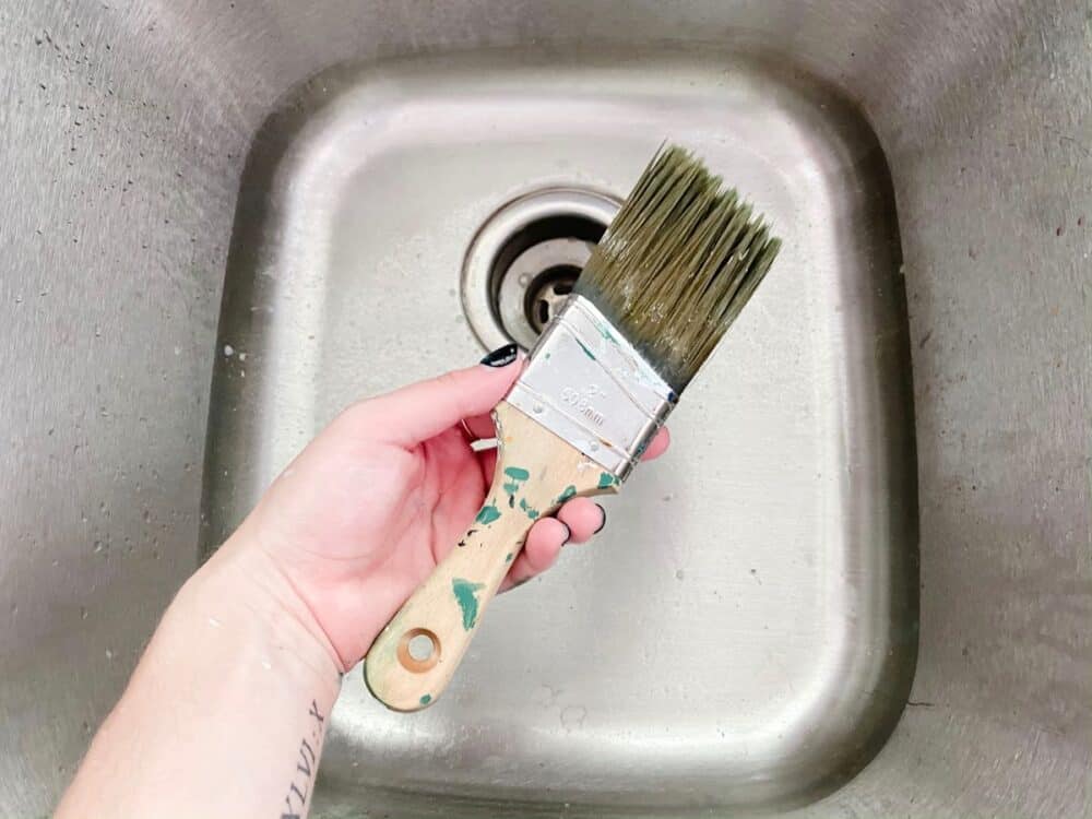 woman's hand holding a freshly-cleaned paintbrush