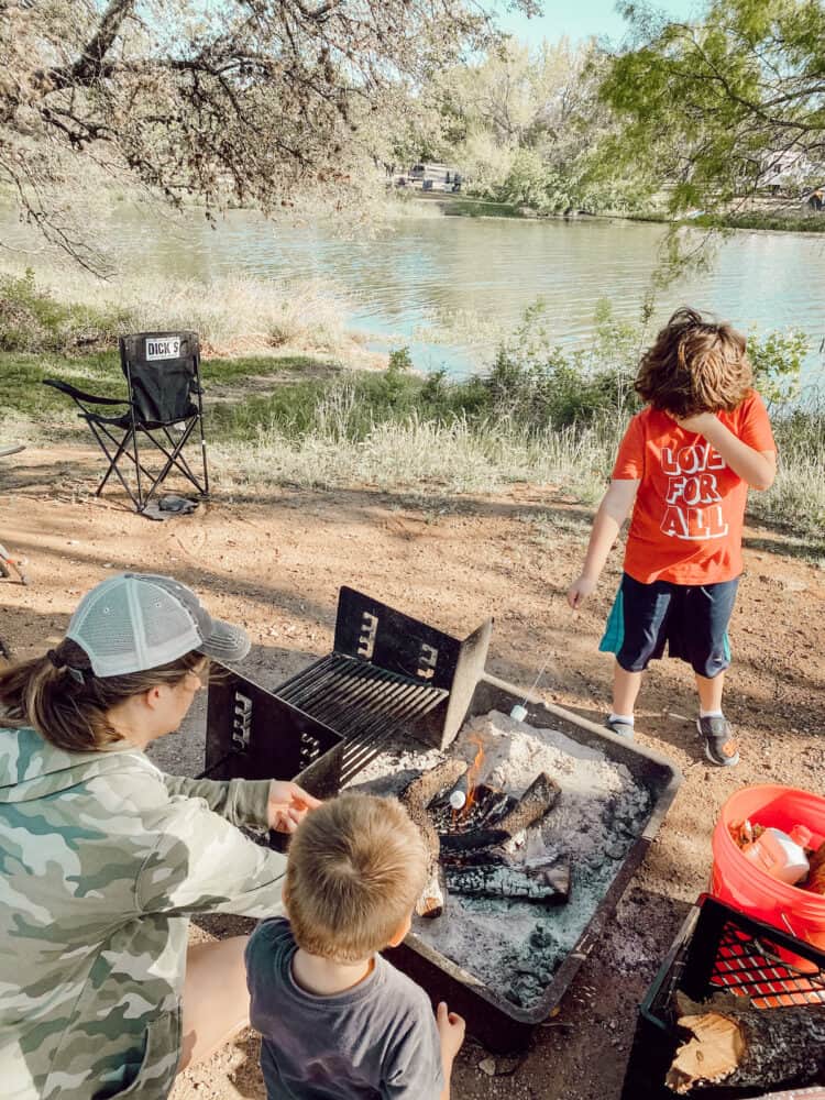 Mom and two young boys roasting marshmallows