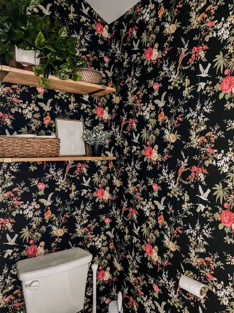 small water closet with shelving above the toilet with faux plants and baskets 