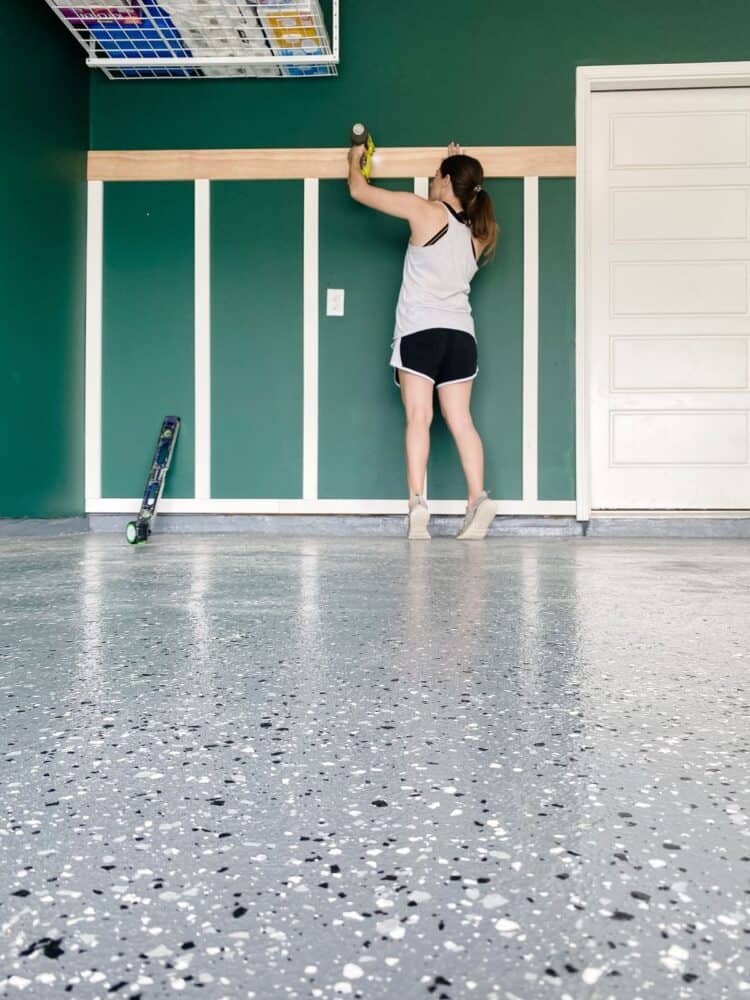 woman using a nail gun to install board and batten accent wall 