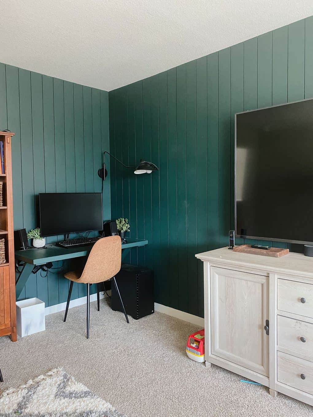 a family room with green vertical shiplap and a built-in desk