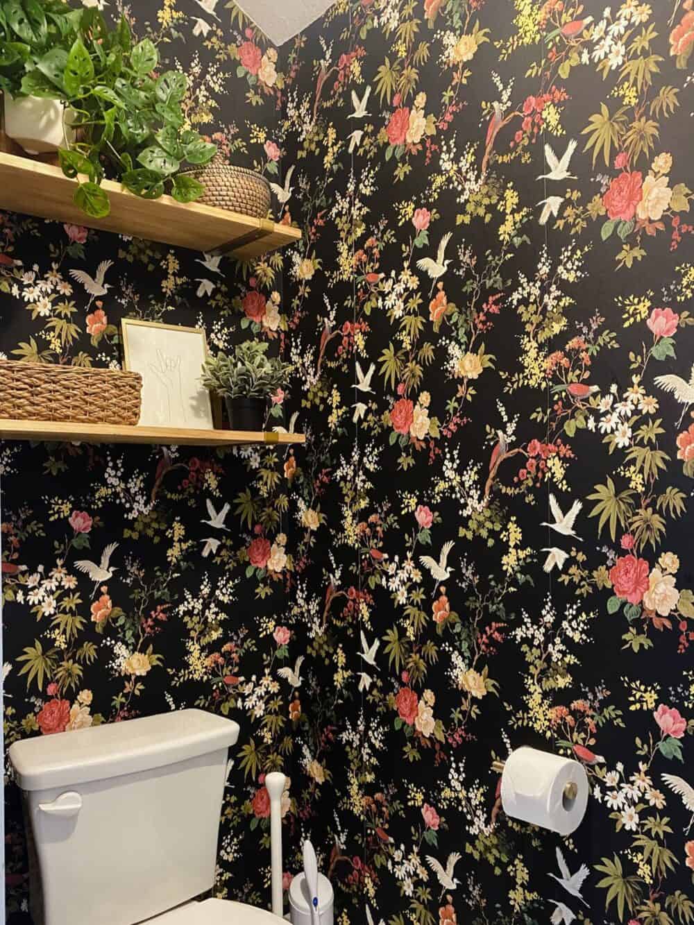 a small water closet with black floral wallpaper