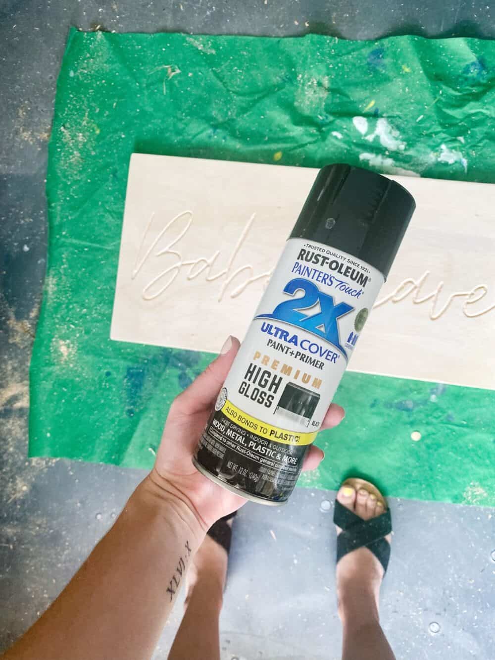 woman's hand holding a can of black spray paint 