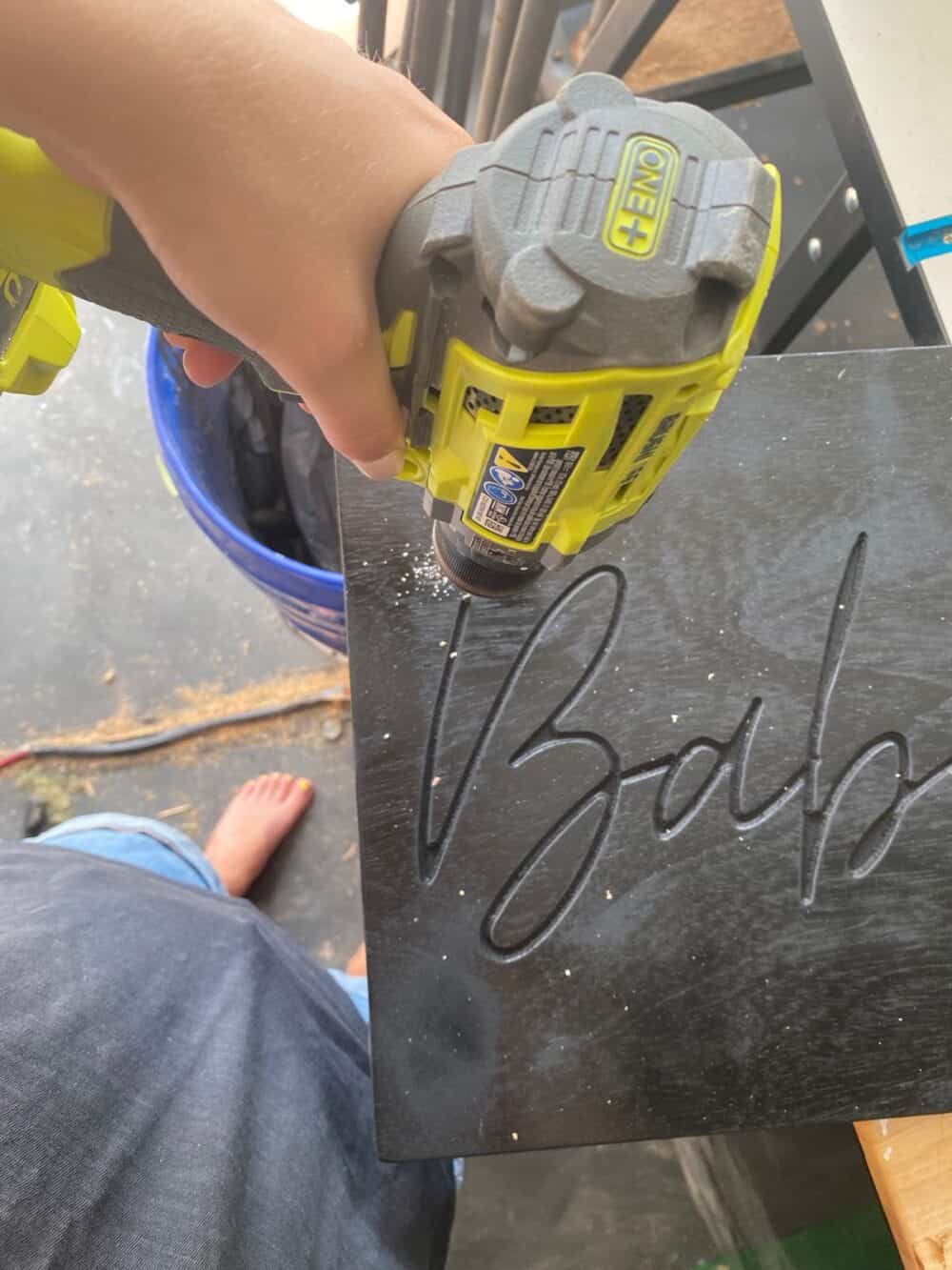 hand holding a Ryobi drill preparing to drill a hole in a DIY neon sign