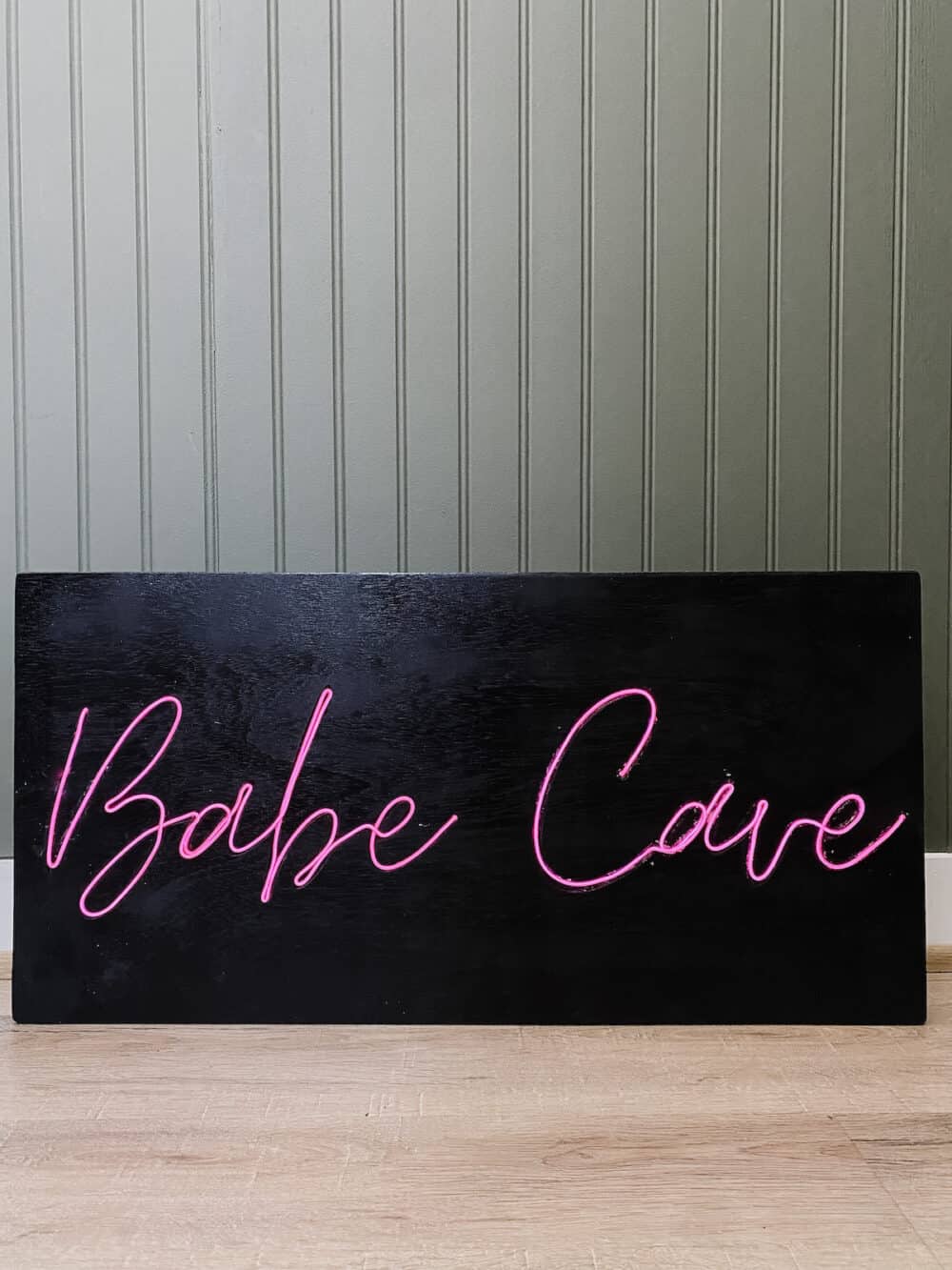 close up image of DIY neon sign that states "babe cave" in pink neon