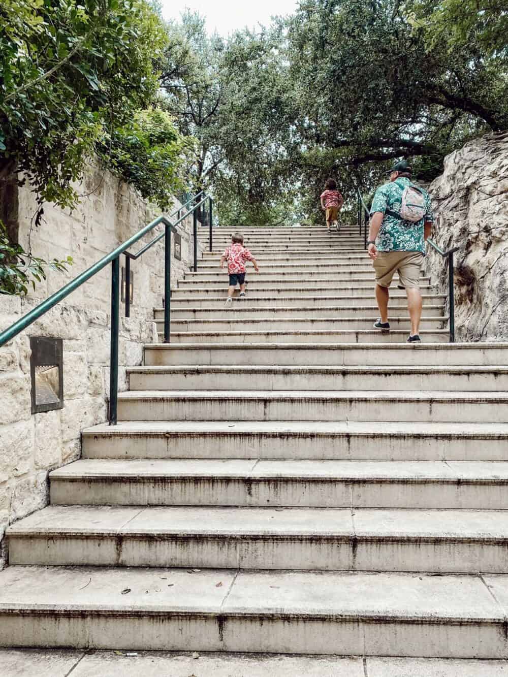father and two young boys walking up a staircase at the SAn ANtonio riverwalk