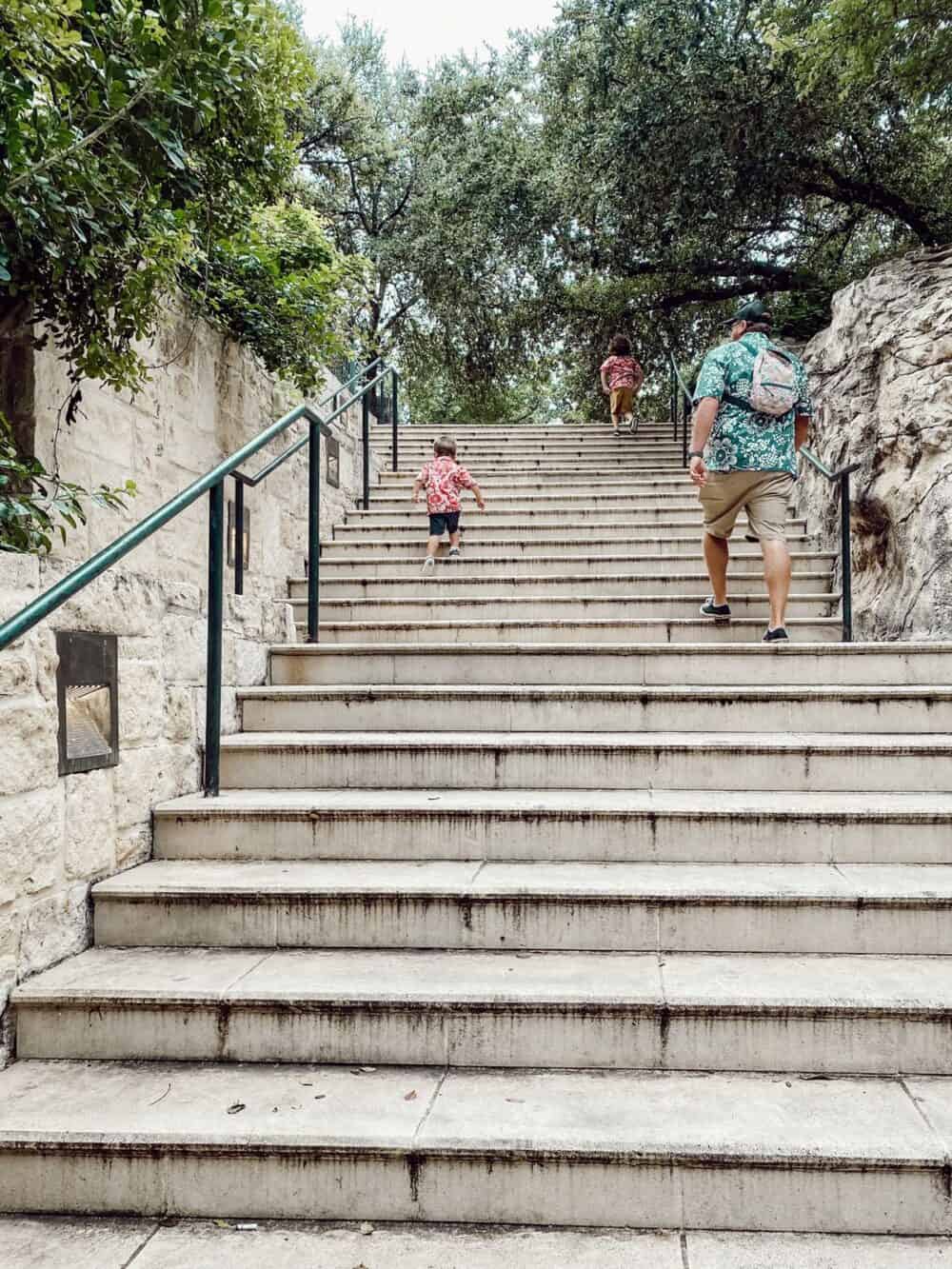 father and two young boys walking up a staircase at the San Antonio riverwalk