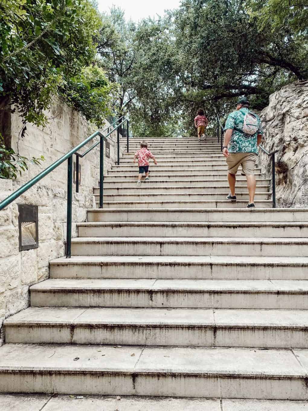 father and two young boys walking up a staircase at the SAn ANtonio riverwalk