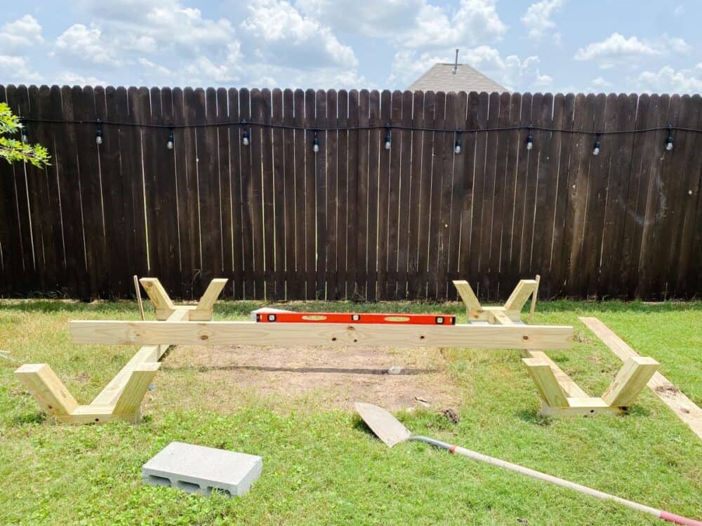 Supports for DIY playhouse laying in grass with a board and level between them 