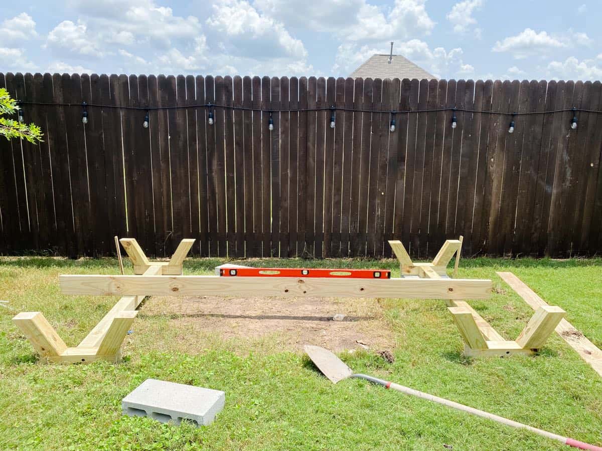 Supports for DIY playhouse laying in grass with a board and level between them