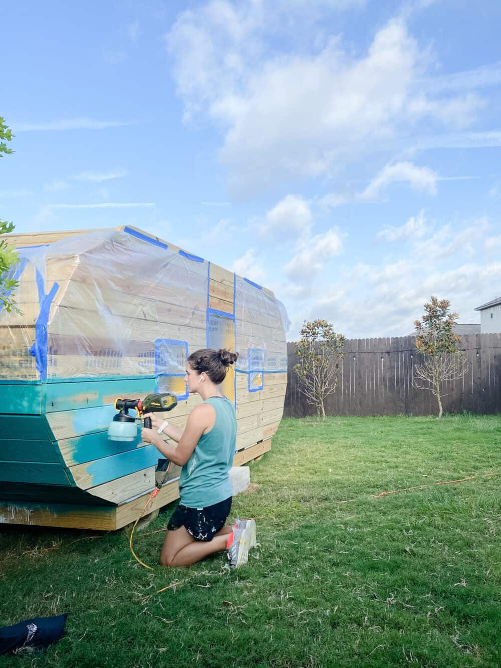 Woman painting a playhouse with a Wagner paint sprayer