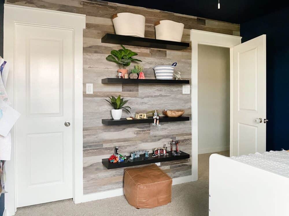 boys bedroom with a faux wood accent wall and floating shelves with legos