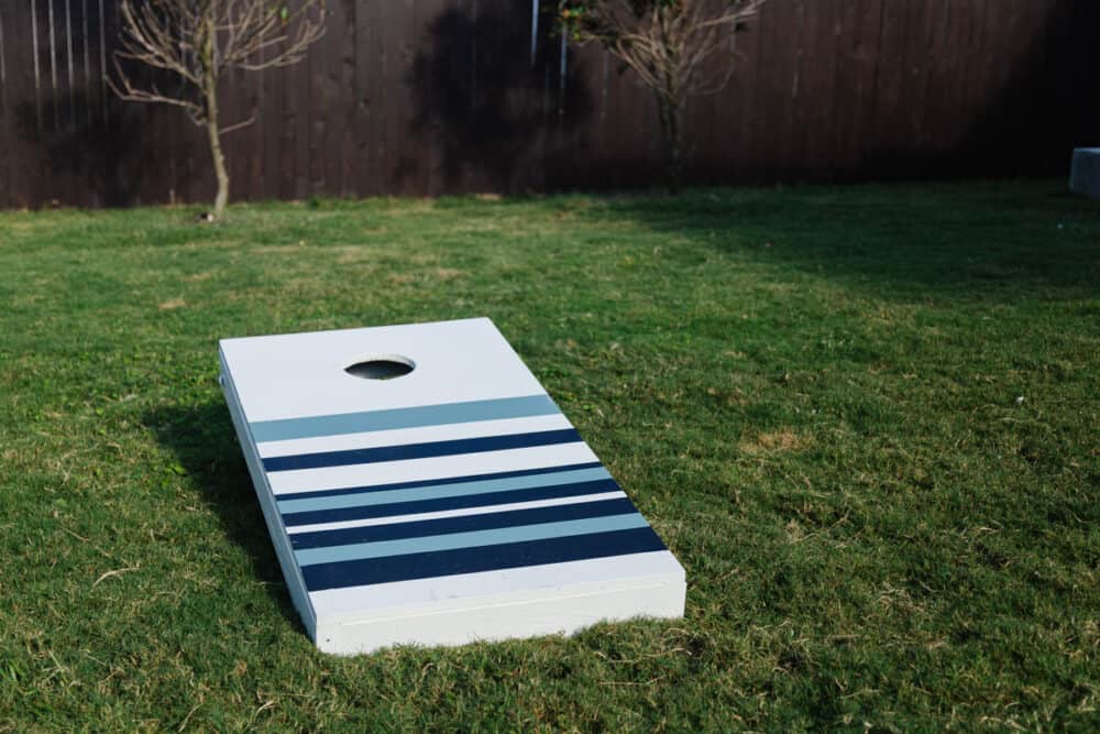 a striped cornhole board sitting on a grassy lawn