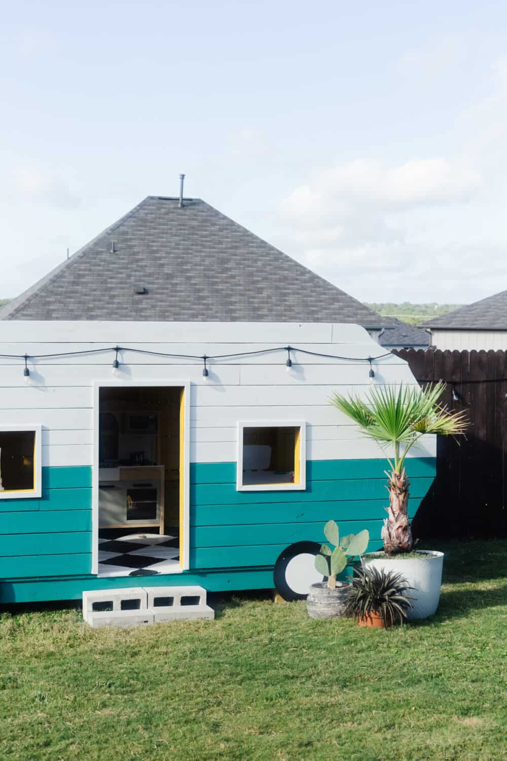 A playhouse shaped and styled like a vintage camper 
