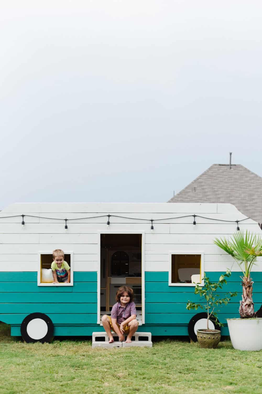 Two young boys posing with a playhouse camper