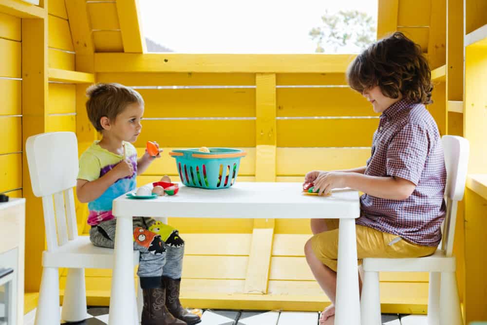 two young boys playing in a seating area of a camper playhouse