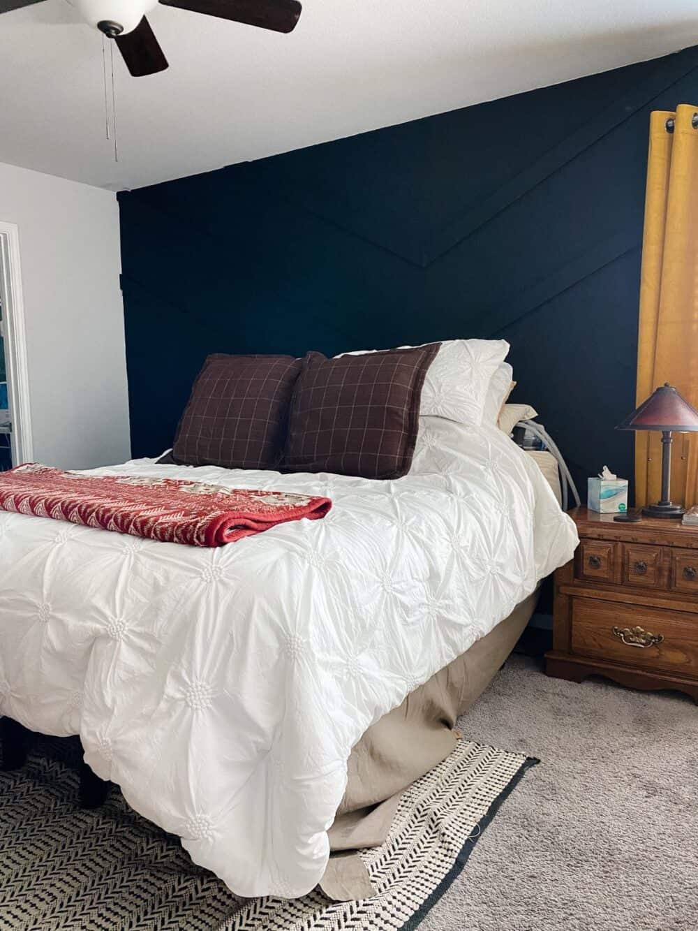 A primary bedroom with a black geometric accent wall