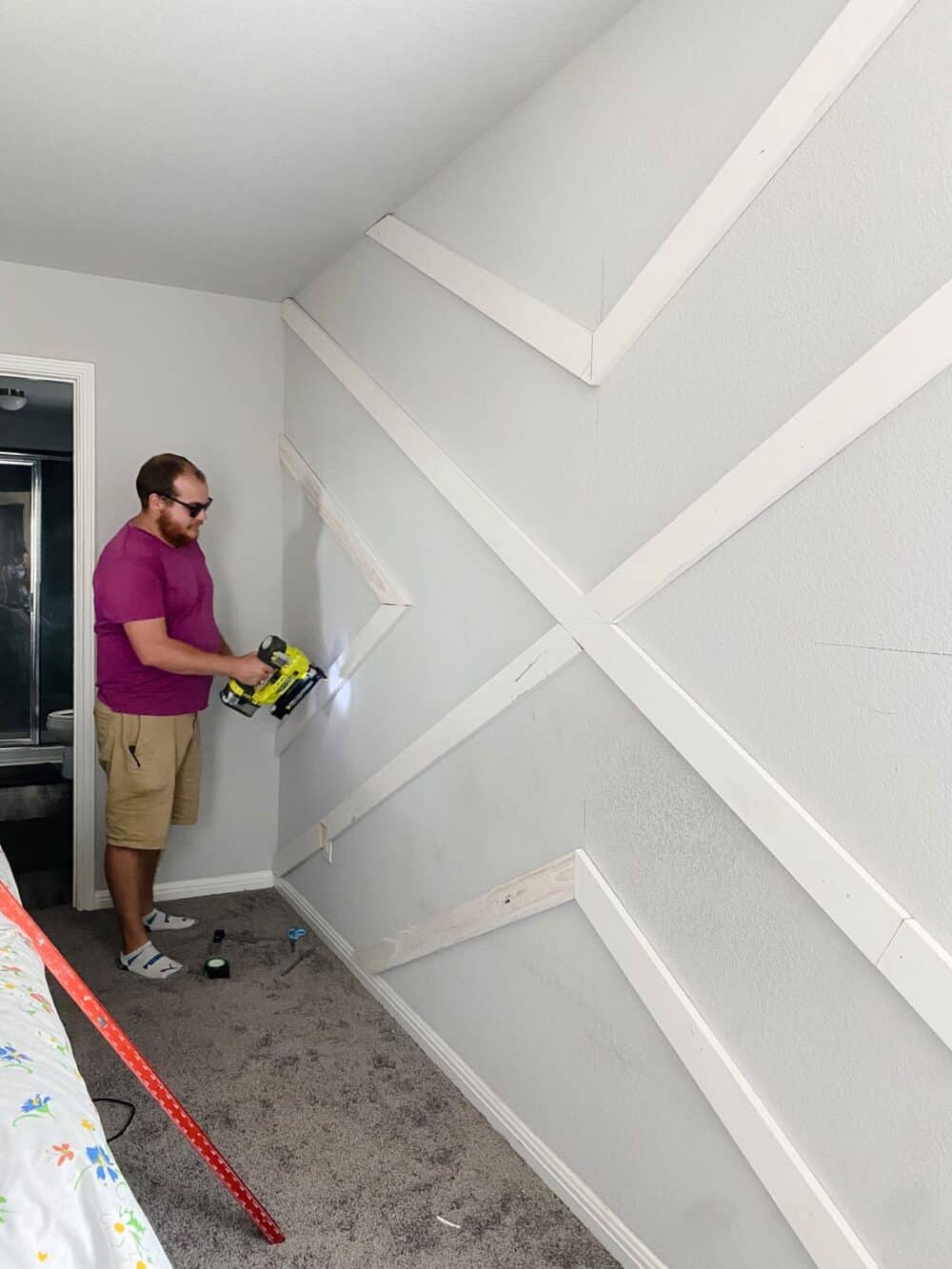 Man installing trim on geometric accent wall 