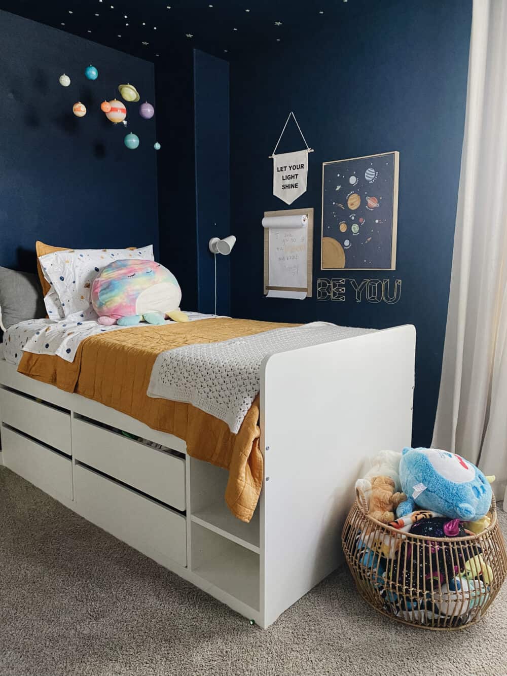 child's bedroom with a basket of stuffed animals at the foot of the bed