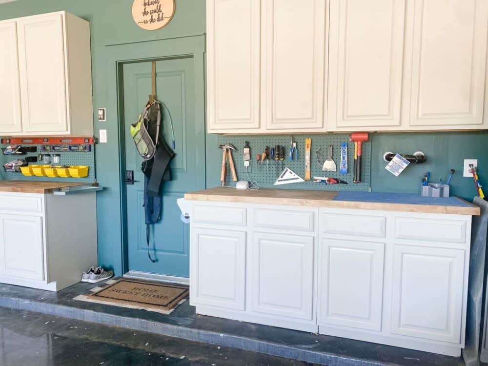 A garage wall with pegboard hung between kitchen cabinets