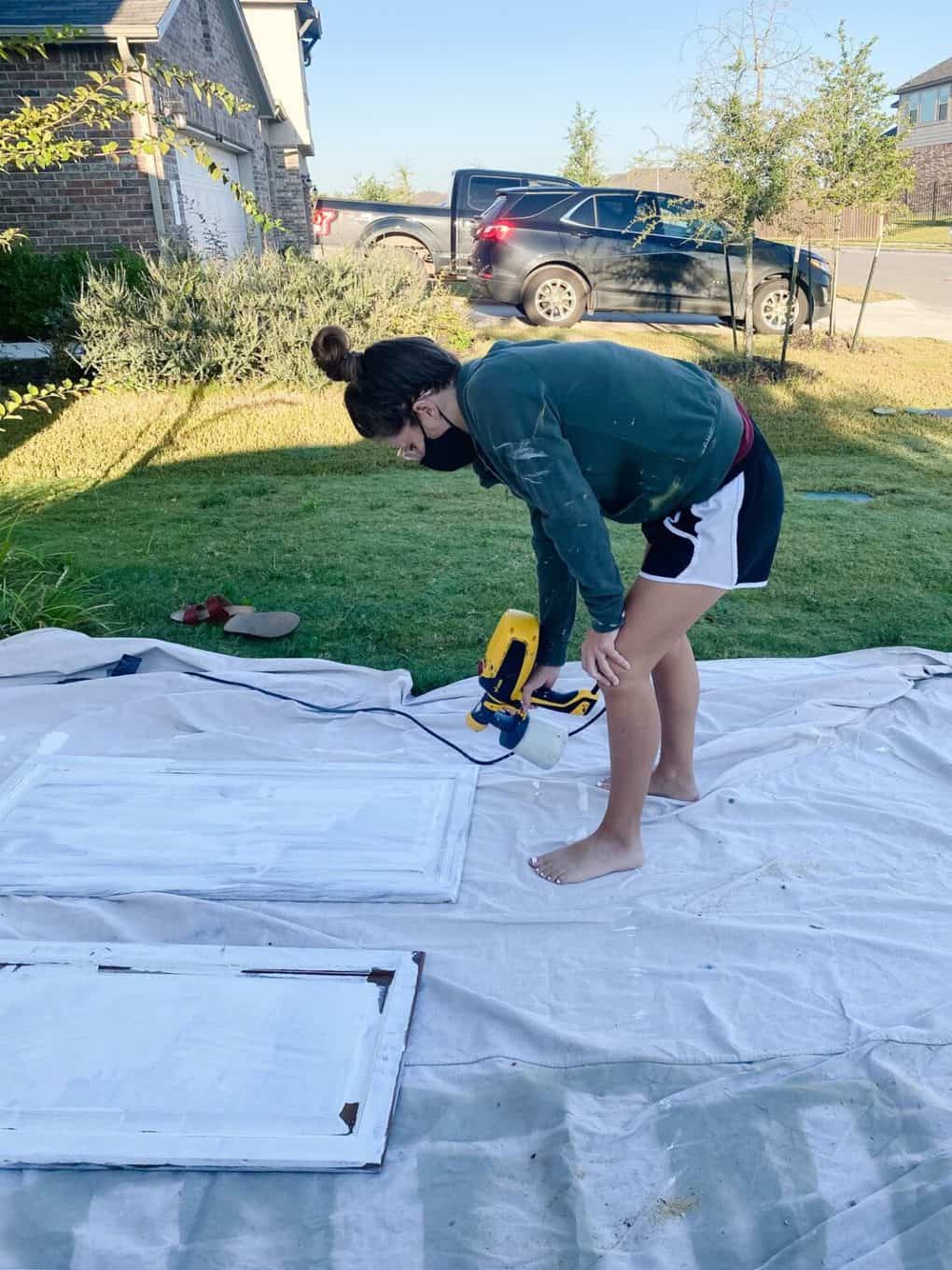 Woman using a Wagner paint sprayer to paint cabinet doors