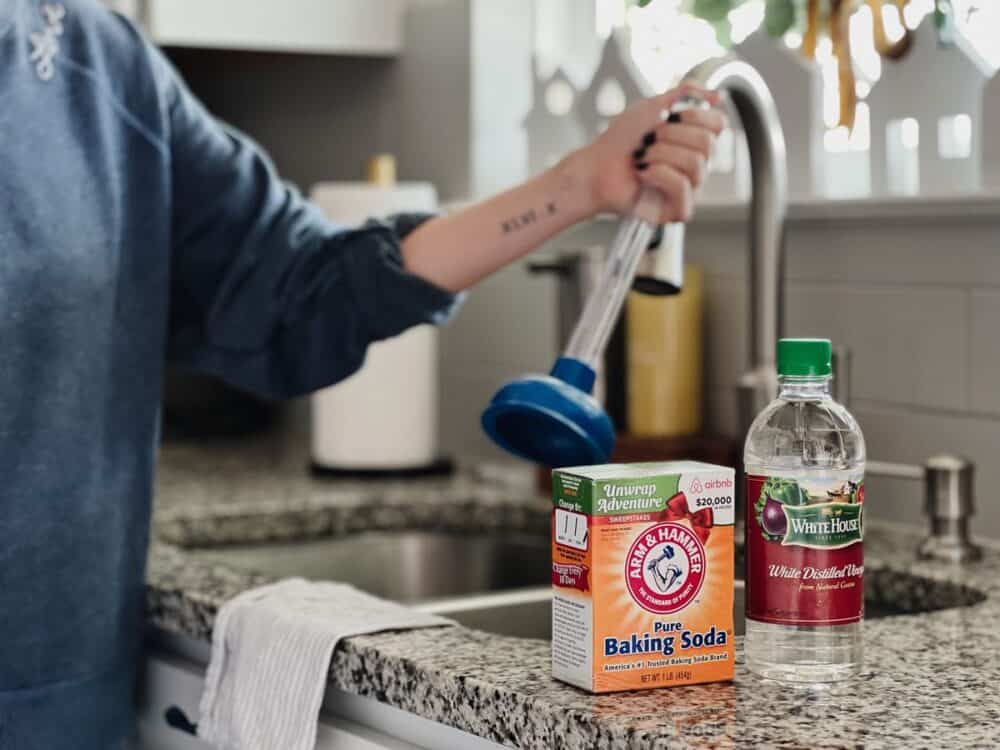 Baking soda and vinegar next to a sink to demonstrate how to unclog a sink