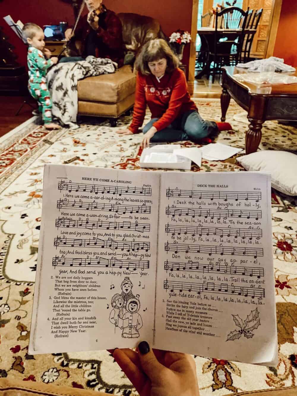 hand holding Christmas sheet music at a family gathering