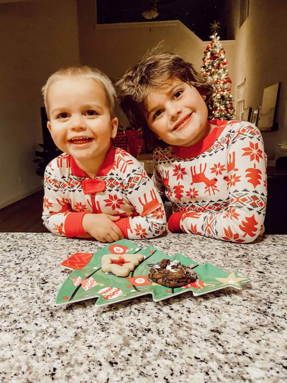 Two boys smiling with a plate of cookies for Santa 