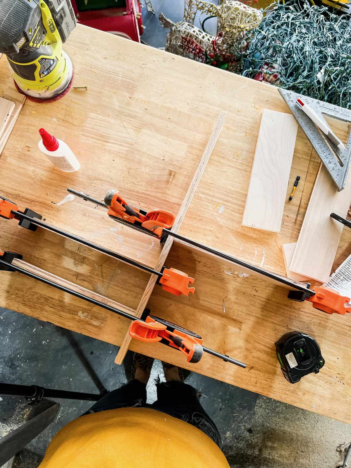 Scraps of wood clamped together to create a diy wooden drawer organizer
