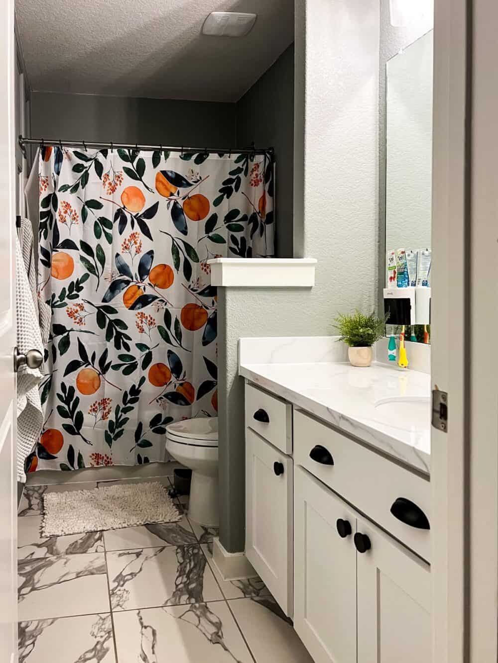 Bathroom with bright citrus shower curtain, and a faux marble epoxy countertop 