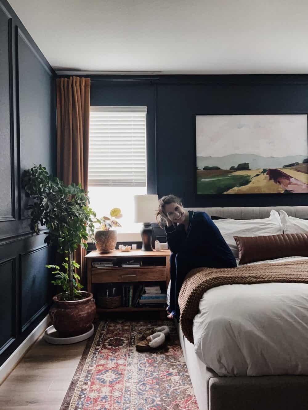 Woman sitting on the side of a bed wearing long pajamas