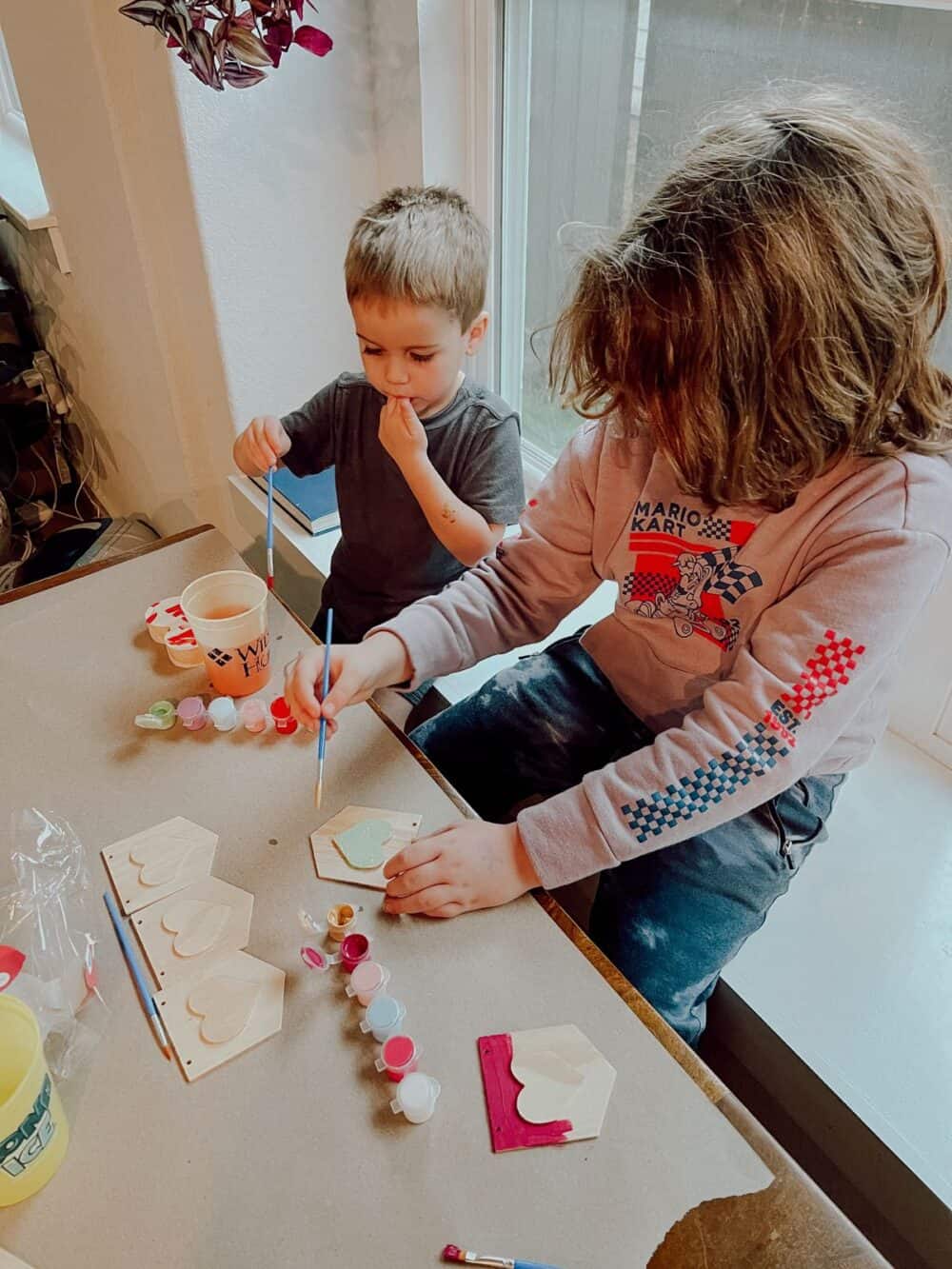 Two young boys painting hearts for DIY Valentine's Day mantel decor