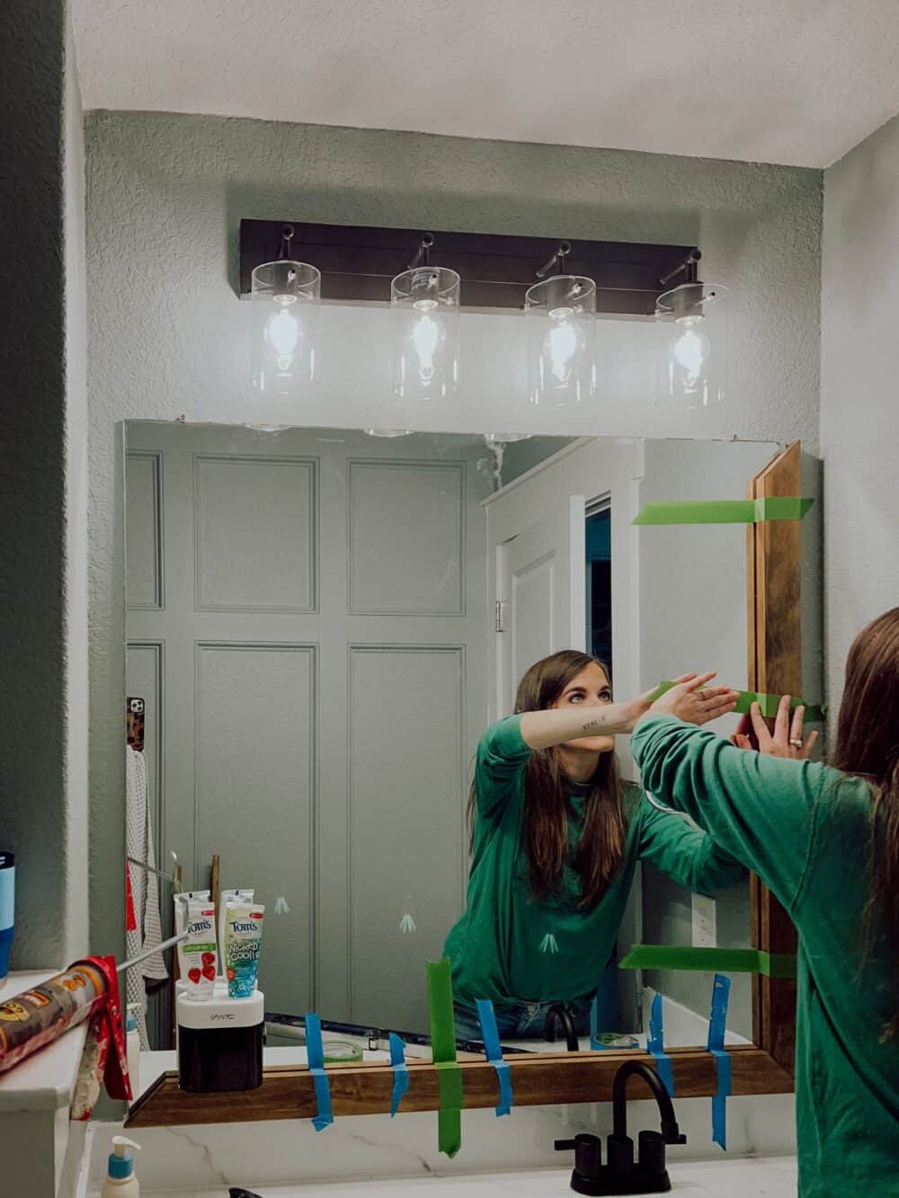 Woman attaching mirror frame to bathroom mirror 