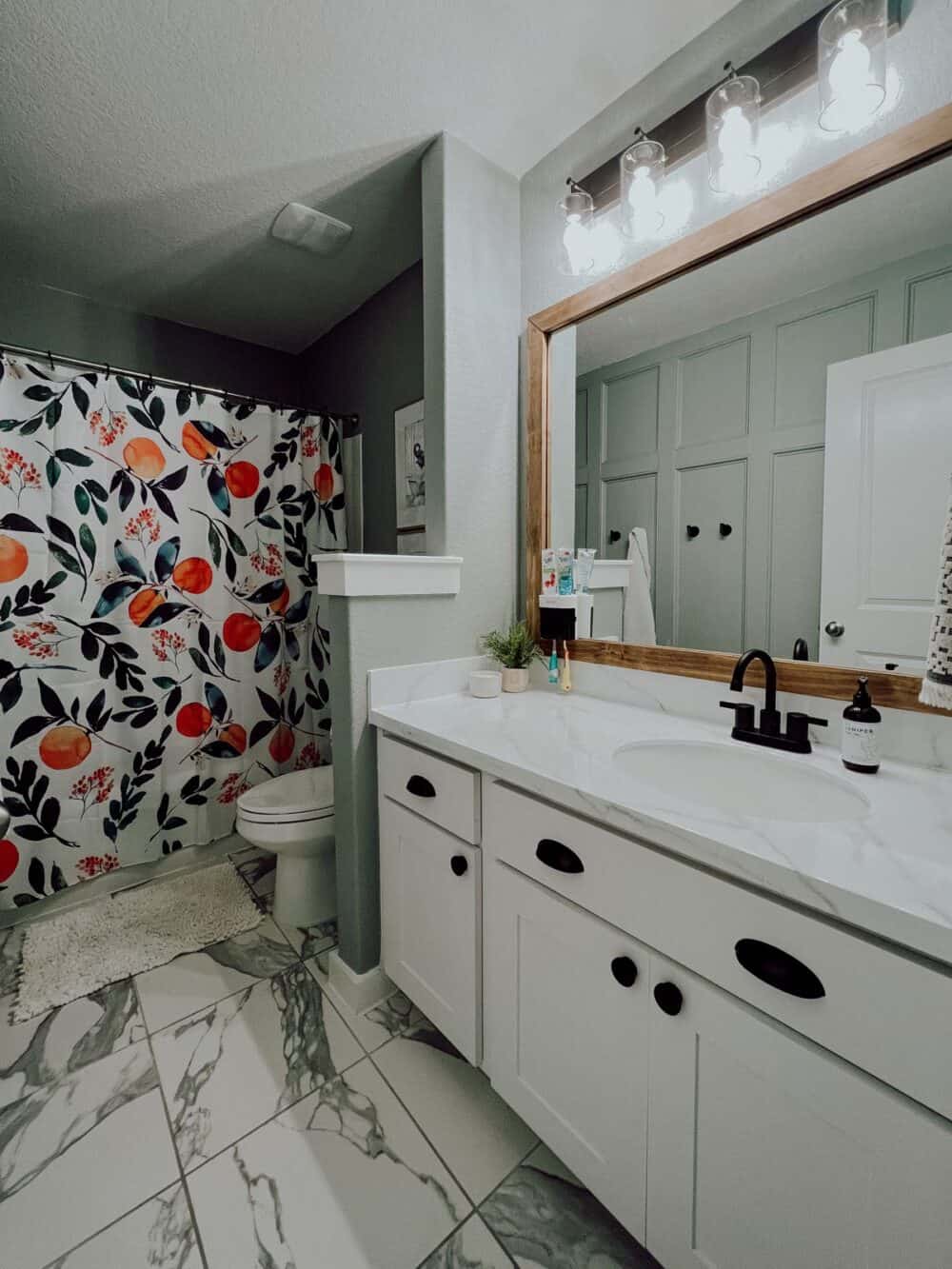 Bathroom with a citrus shower curtain and wood framed mirror 