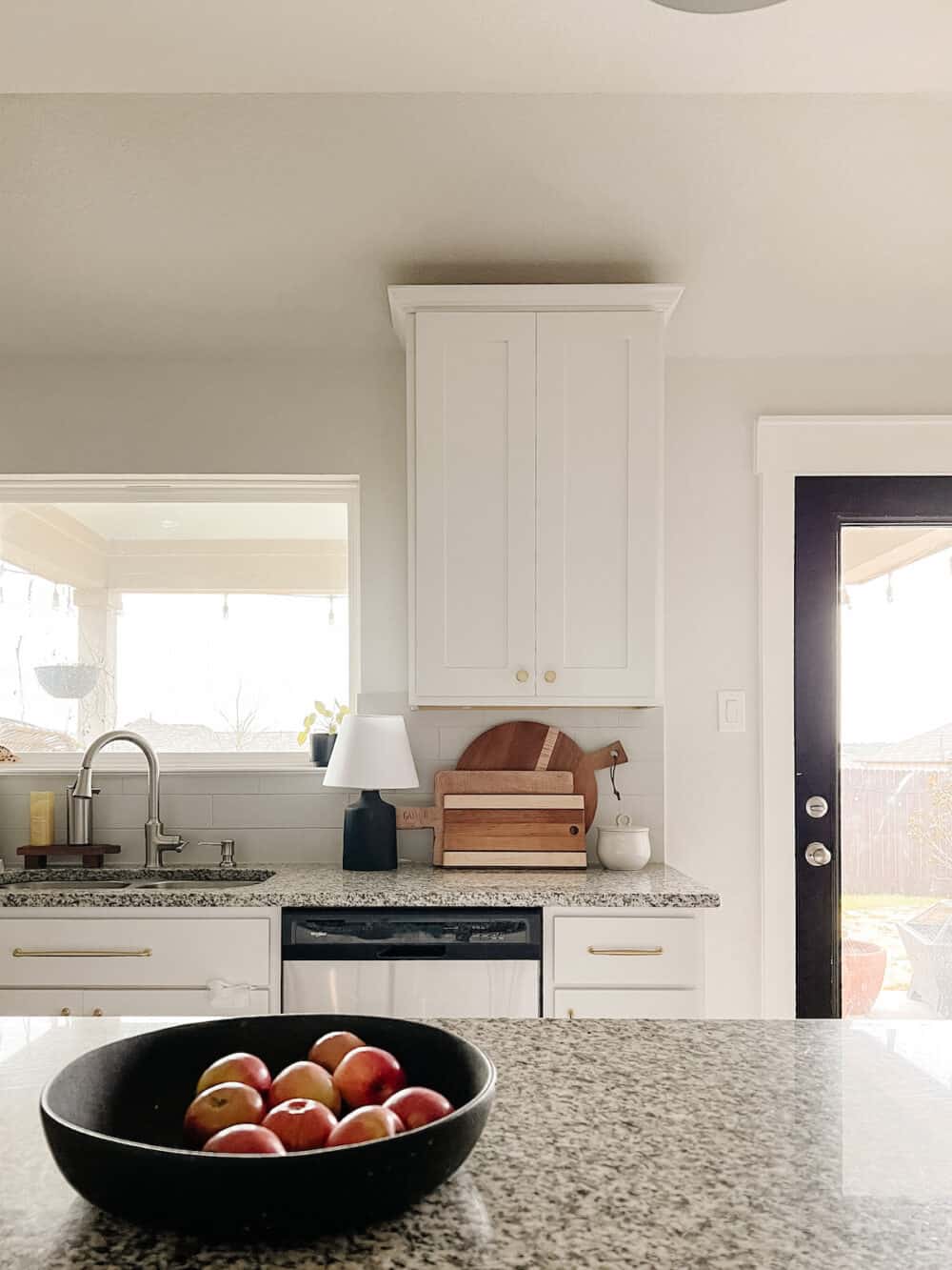 White kitchen with wood accents and a small lamp on the counter next to some wooden cutting boards