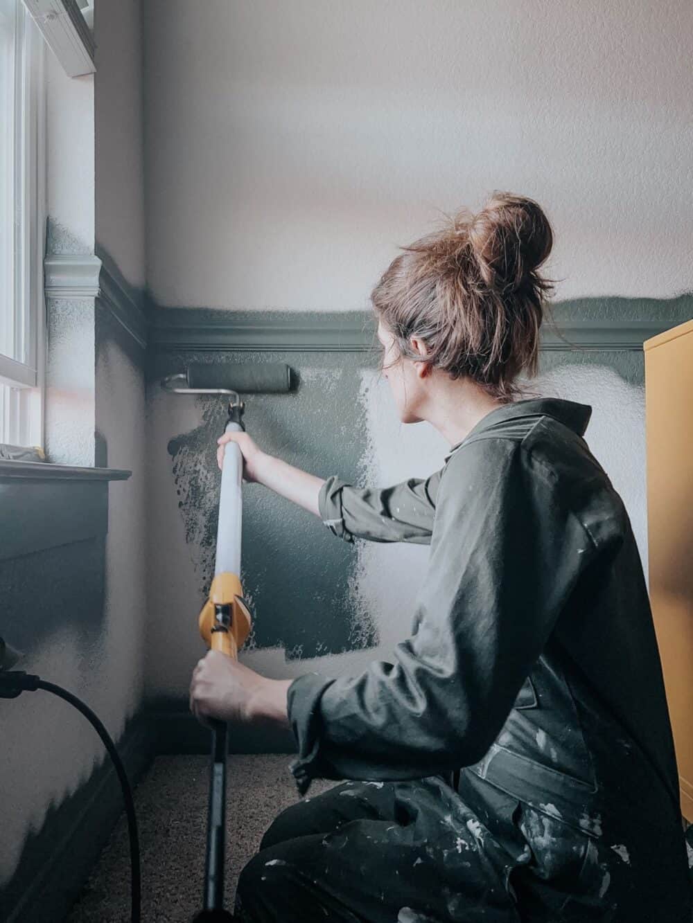 woman using a wagner roller to paint walls of a room green