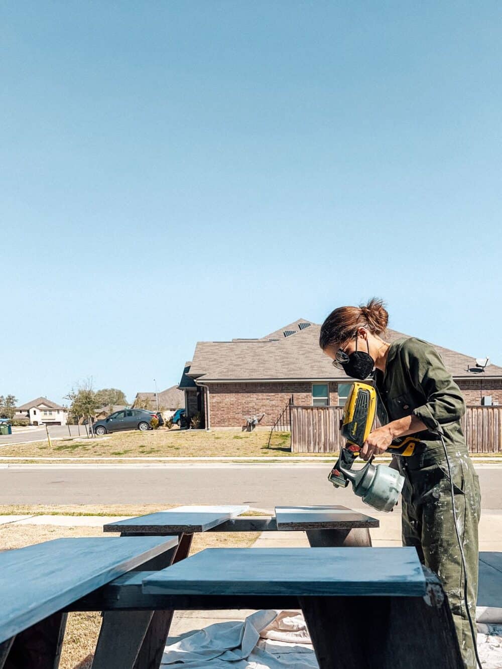 Woman using a paint sprayer to paint bookcase shelves