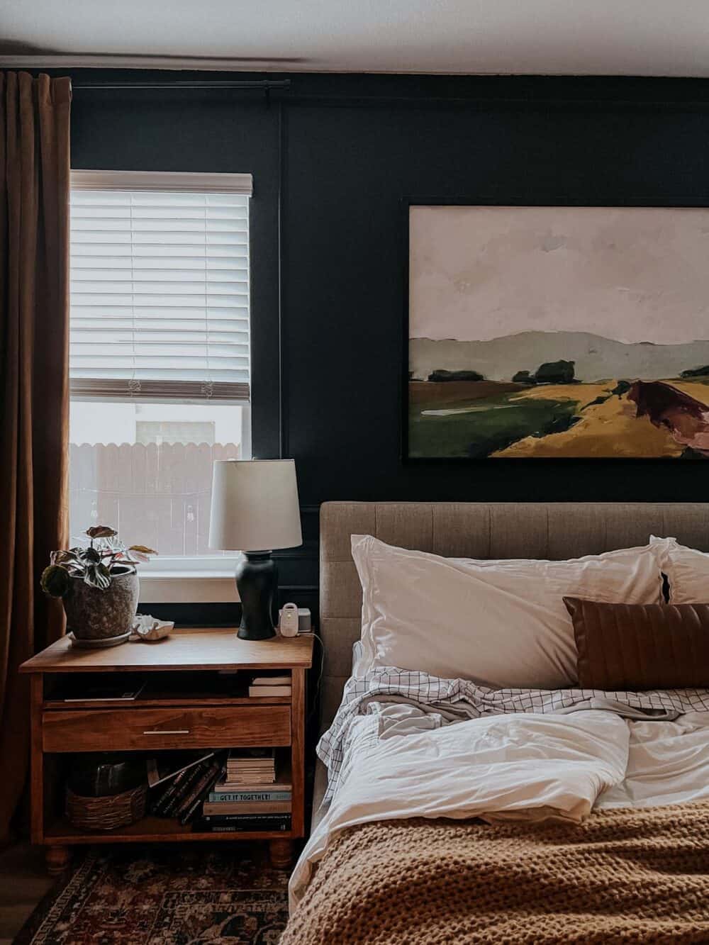 A slightly messed up bed in a dark and moody bedroom 