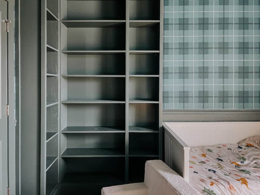 toddler bedroom with built in bookcases, green walls, and green plaid wallpaper
