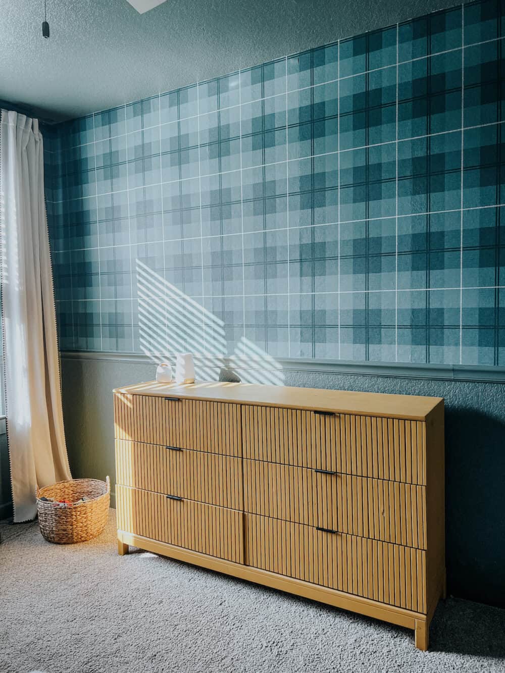 Kid room with green plaid wallpaper and a yellow dresser 