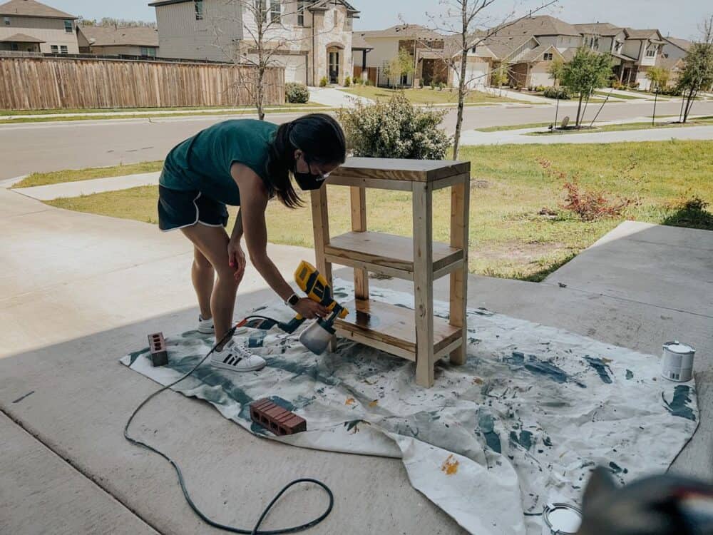 Woman staining a plant stand with a Wagner sprayer 