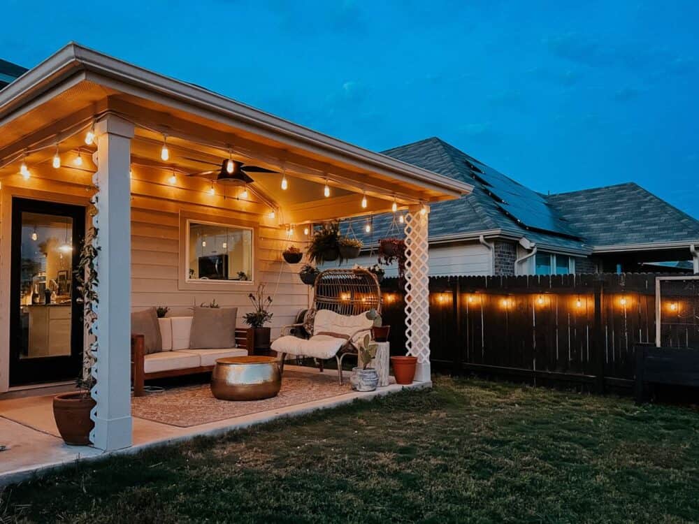 backyard with string lights hanging on the covered patio and along the fence