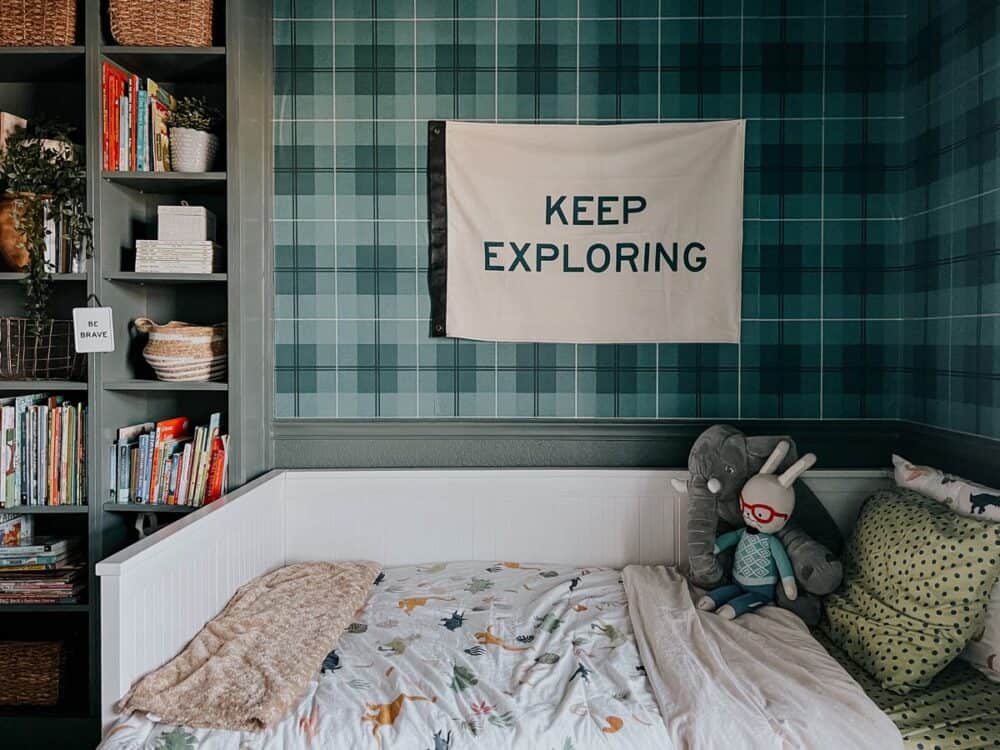 Toddler bed with a "keep exploring" flag hanging above it